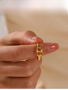 Detailansicht eines verstellbaren goldenen Schweinenasen-Ringes am Finger getragen
