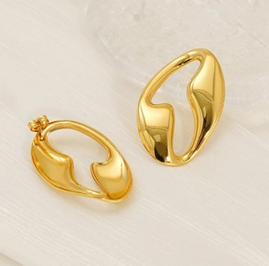 Macro detail of high-polish 18K gold irregular geometric earrings with artistic curves