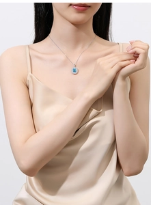 Close-up of model wearing an S925 silver necklace with an oval sky blue gemstone pendant