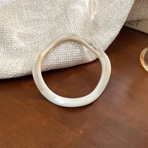 Detail of artistic amber resin bangle with beige marble texture on a rustic wooden surface