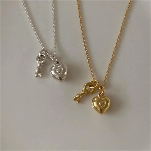 Detail of silver and gold heart and key pendants on minimalist fine chain necklaces