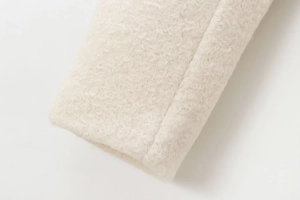 Close-up of cream-colored double-breasted wool coat showing soft sherpa texture details
