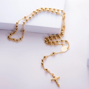 Golden titanium steel bead necklace with cross and Virgin Mary pendant on white stand
