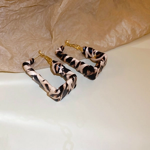 Vista macro de pendientes de aro geométricos de leopardo con cierres de metal dorado