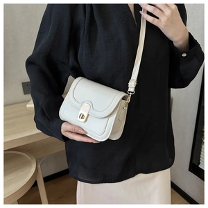 Detailed shot of cream-white square bag featuring a gold twist-lock and fine stitching