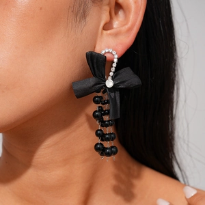Detail of elegant black ribbon bow earrings with cascading diamond-studded fringe tassels