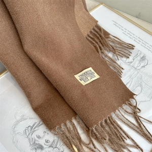 Close-up of brown cashmere-feel scarf with fringe and brand label on vintage book
