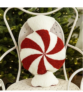 Detail of red and white spiral candy cushion on white metal chair with Christmas tree