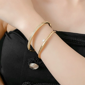 Close-up of gold geometric bangle set featuring pave zircon crystals and a pearl accent