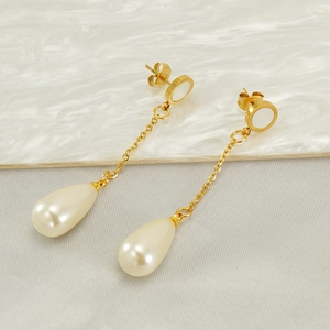 Élégantes boucles d'oreilles pendantes dorées avec perles blanches sur fond de marbre