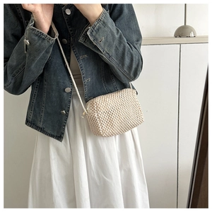 Close-up of cream woven crossbody bag showing textured craftsmanship and zipper closure