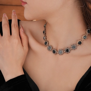 Close-up of vintage flower necklace with dark grey crystals on bronze chain worn by a model