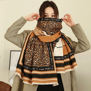 Detail of leopard print scarf with French text patterns and fringe edge shown by model