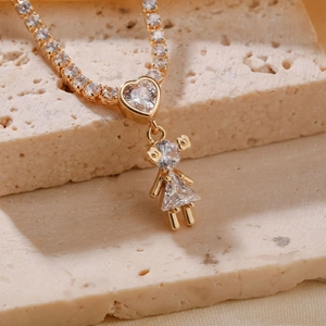 Golden necklace with heart links and crystal-inlaid girl pendant on beige stone background