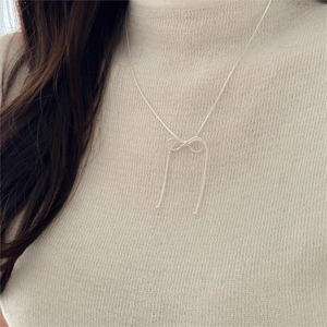 Minimalist 925 sterling silver bow snake chain necklace worn on a cream sweater
