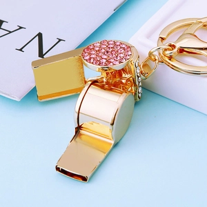 Close-up of golden metal whistle keychain featuring pink rhinestones and snap hook