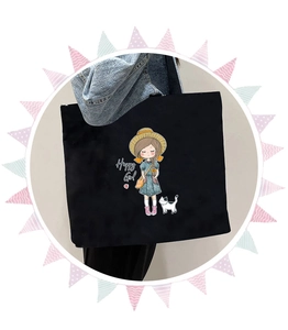 Close-up of a large black canvas tote bag featuring a cute cartoon girl illustration