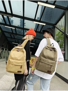 Street style view of khaki and army green canvas backpacks with leather pullers and patches