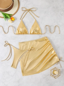 Flat lay of metallic gold bikini set and matching sarong skirt on marble background