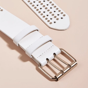 Détail d'une ceinture en cuir blanc avec découpes en étoile, rivets et boucle dorée à deux tiges