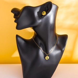 Vintage gold necklace and earrings set with turquoise stone on black mannequin