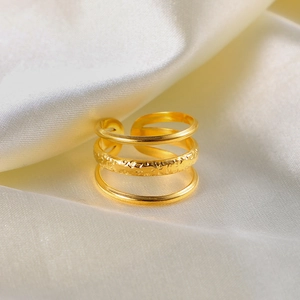 Three-layer gold stainless steel open ring with textured band on silk fabric background