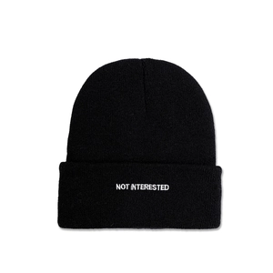 Detail of white NOT INTERESTED embroidery on a black cuffed knit beanie hat