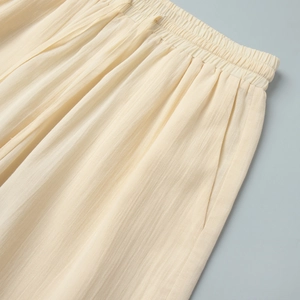 Detail of cream casual pants featuring an elastic waistband and side slit pockets