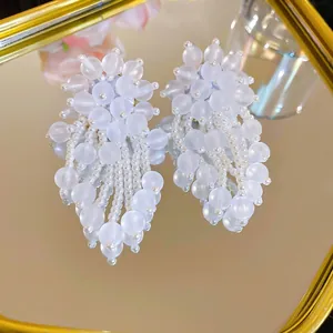 Elegant beaded drop earrings with matte beads and pearls displayed on a mirror