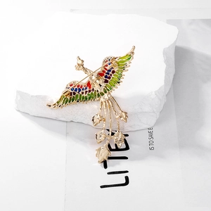 Vintage Phoenix brooch with colorful enamel wings on a textured white stone base