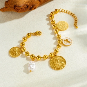 Gold beaded bracelet with cross, pearl, and religious medal charms on a natural wood base