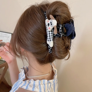 Détail d'une pince à cheveux à carreaux avec chiot en peluche et nœud bleu