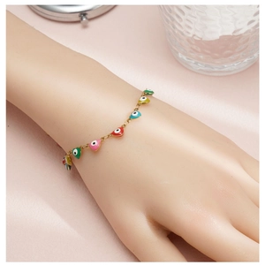 Detailed shot of gold bracelet with colorful enamel heart charms and evil eye designs