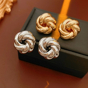 Detailed view of silver and gold metal swirl knot earrings on black jewelry gift box