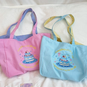 Detail of canvas tote bags with cake embroidery and checkered lining on the handles