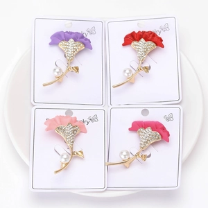 Set of four carnation brooches with sparkling rhinestones and pearls on a ceramic plate