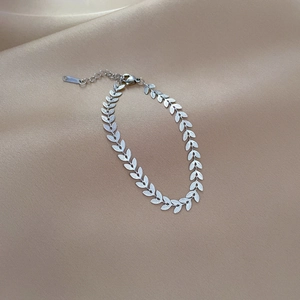 Detailed macro view of silver leaf chain bracelet with S-STEEL mark on satin