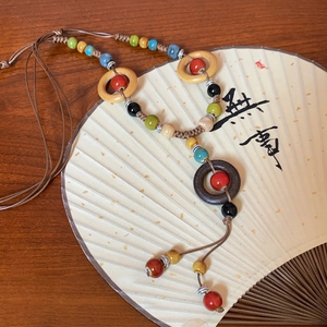 Detailed close-up of bohemian ceramic beaded necklace with leaf pendant and woven tassels