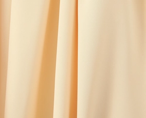 Gros plan détaillé montrant la texture du tissu beige et le drapé vertical fluide
