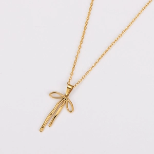 Detailed close-up of a polished gold bow pendant on a delicate stainless steel chain
