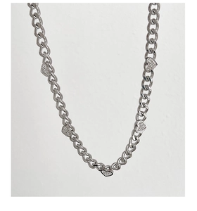 Detail of silver Cuban chain necklace featuring heart pendants with white rhinestones