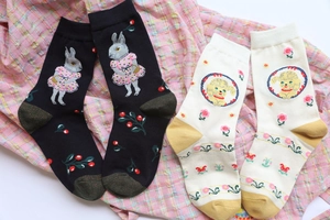 Close-up of cotton socks with forest animal patterns like rabbit and dog on pink plaid fabric