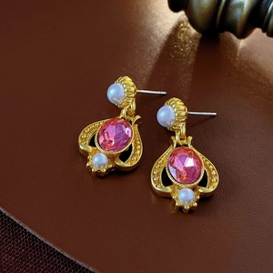 Close-up of vintage gold earrings with pink gemstones and white pearls on leather