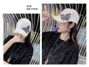 Detail of white satin baseball cap featuring a delicate 3D rhinestone butterfly ornament