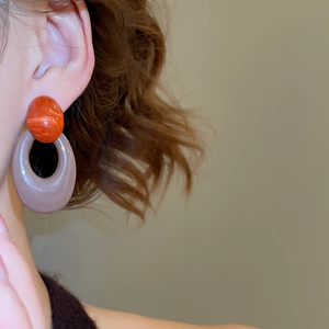 Close-up of vintage acrylic oval drop earrings with marble texture on model's ear