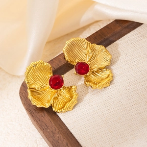 Vintage golden petal stud earrings with red zircon center on a neutral satin background