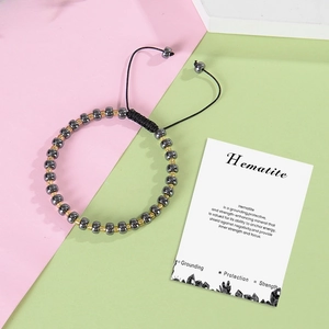 Macro shot of hematite beaded bracelet with golden spacers and adjustable black cord on card