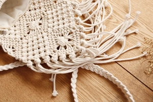 Detailansicht der handgewebten Macramé-Umhängetasche mit Fransen und Baumwollfutter im Boho-Stil