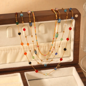 Bohemian gold chain necklace with colorful natural stones on beige velvet jewelry box