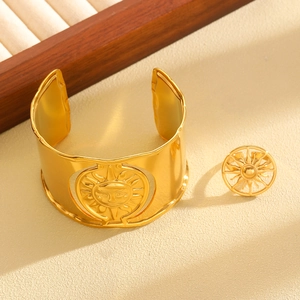 Detail of luxury gold jewelry set featuring sun god embossed bangle and matching ring